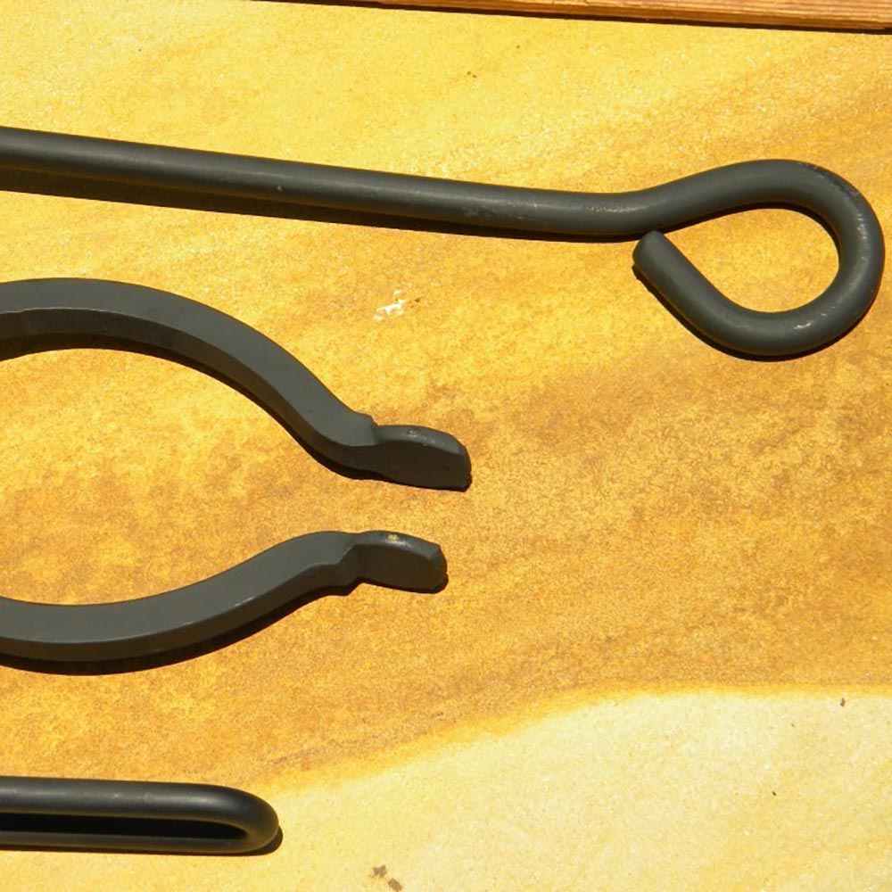Black metal fireplace tools with curved poker ends and loop handle