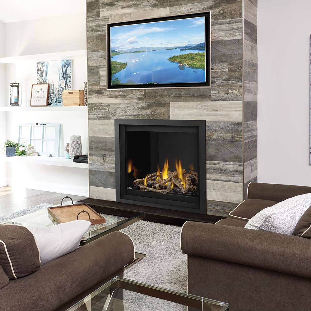 Gas fireplace insert with black frame, burning logs in gray stone surround