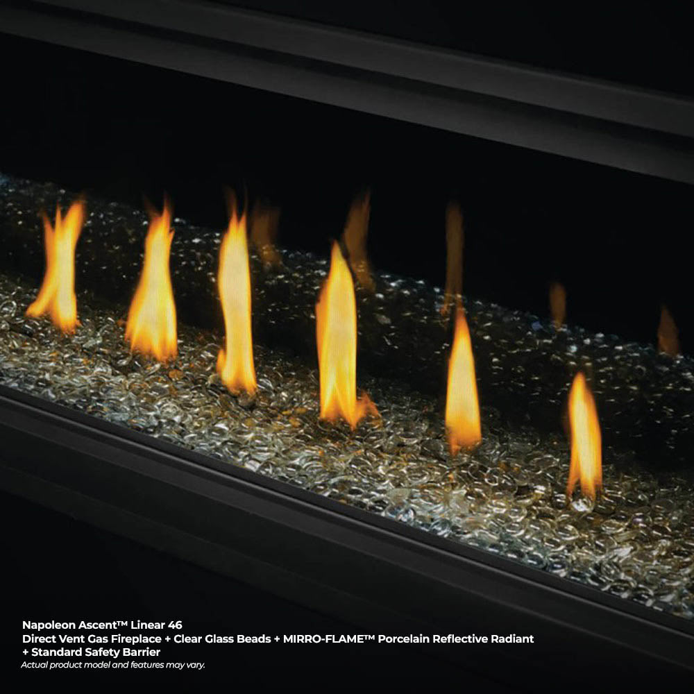 Glass-front fireplace burner with tall flames over dark gravel and stones