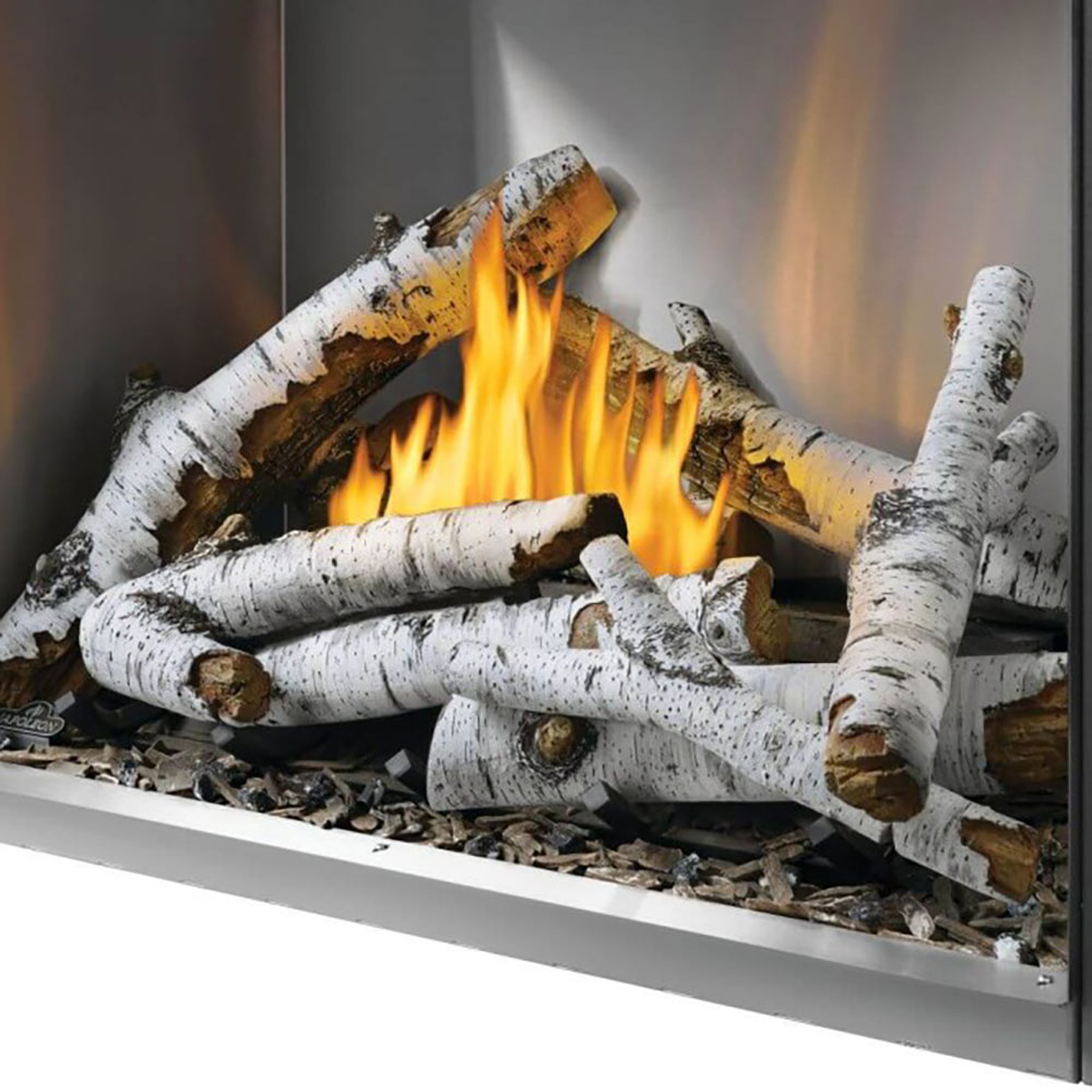 Outdoor gas fireplace log set in firebox with white logs, stones, and orange flames