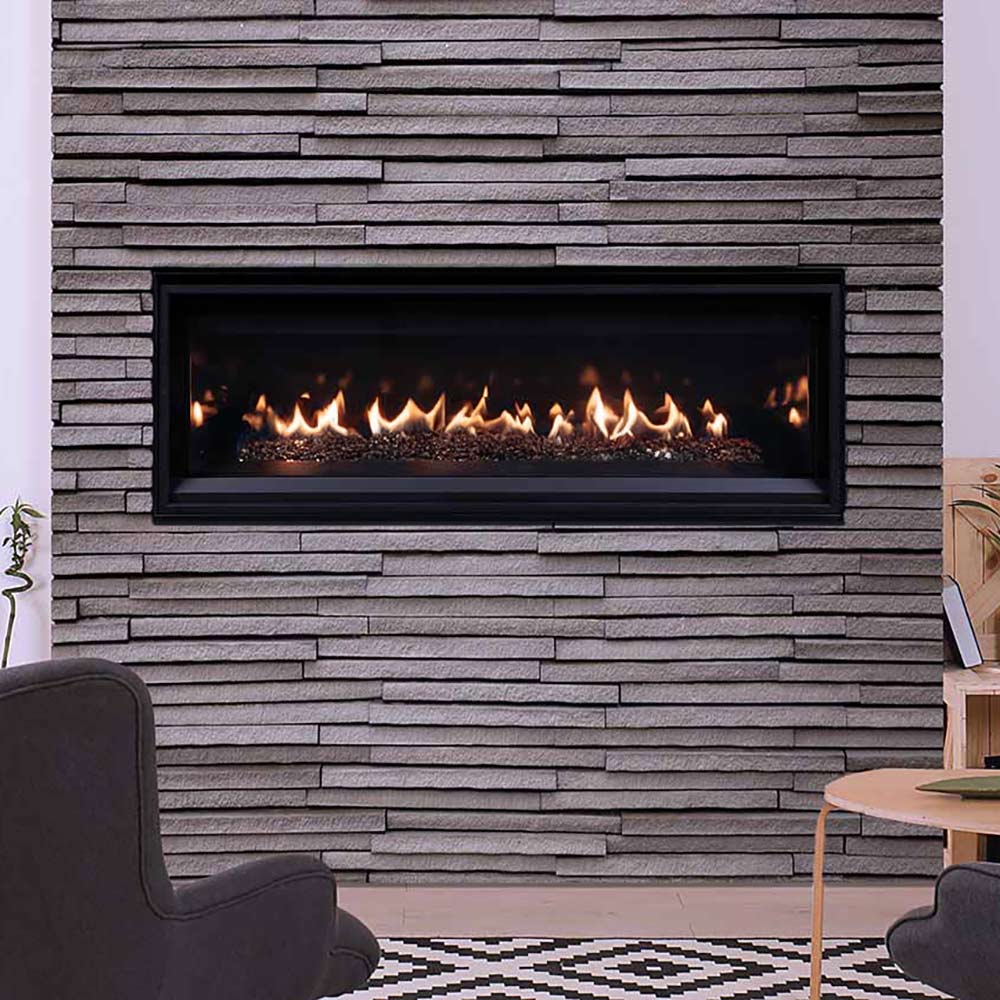 Direct vent gas fireplace insert with burning flames and crushed glass set into a stone wall