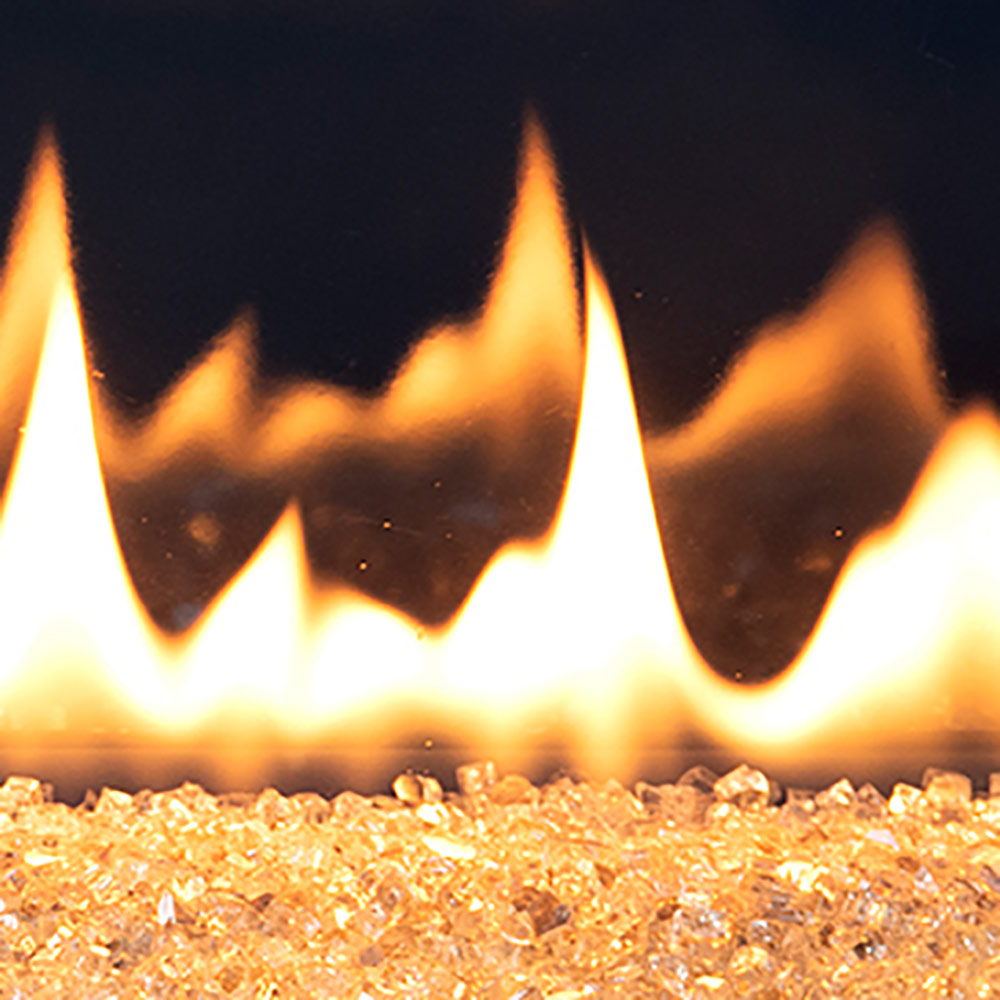 Gas fireplace flames above tan crushed glass media, close-up view