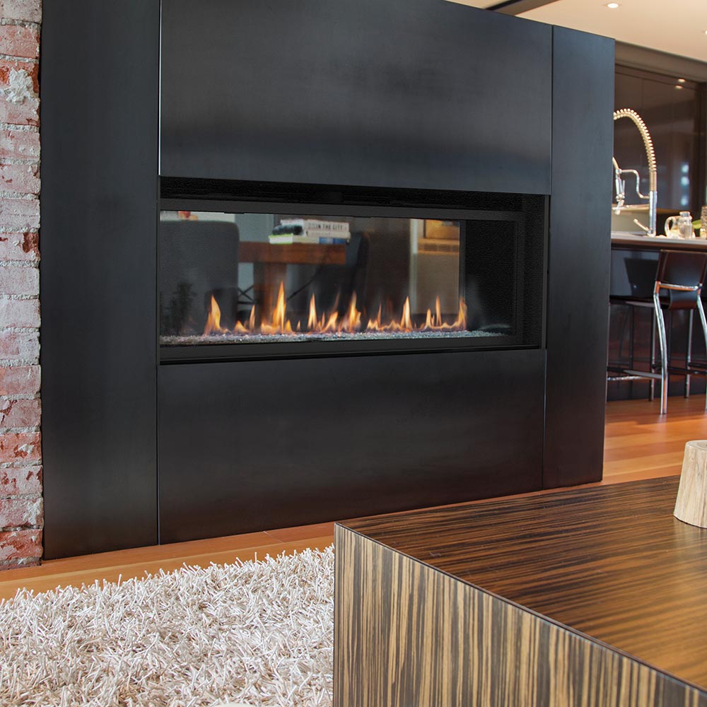 Matte black see-through gas fireplace with open flame window and surrounding panel