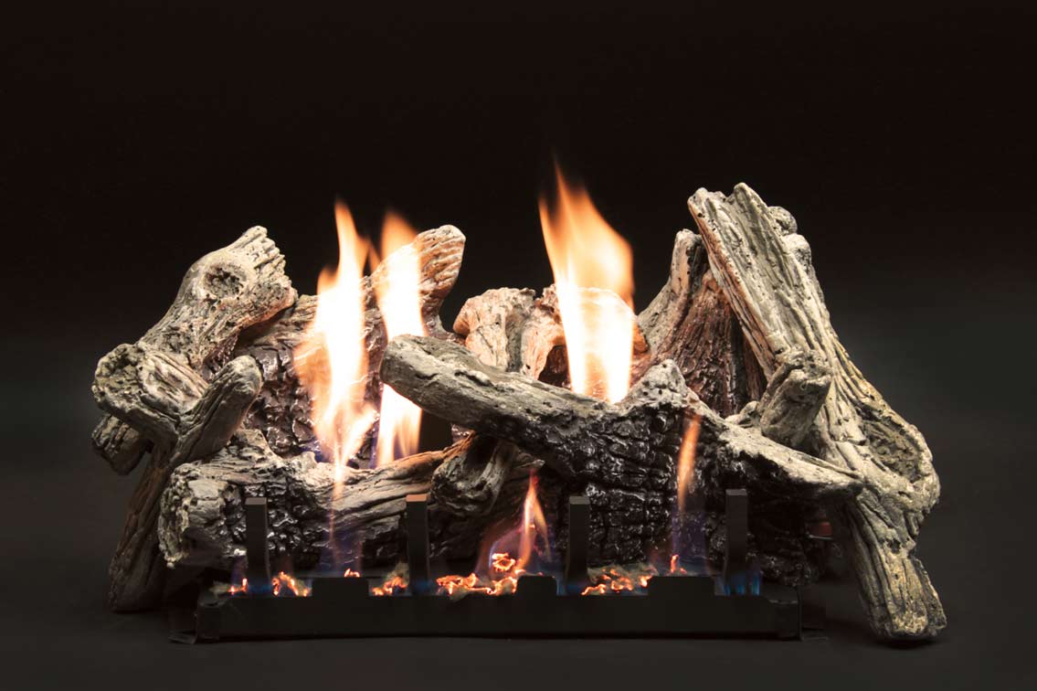 Gas fireplace log set with burning flames and driftwood-style concrete logs