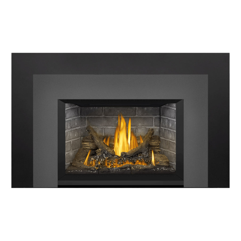 Gas fireplace insert with dark frame, gray brick firebox, flames rising from burning logs.