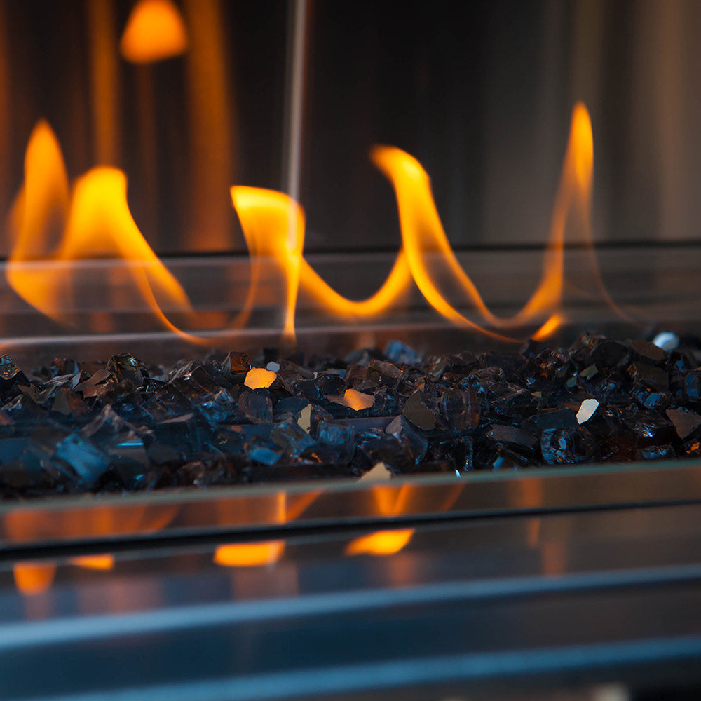 Blue broken fireglass bed in a linear gas fire pit, visible beneath active flames.