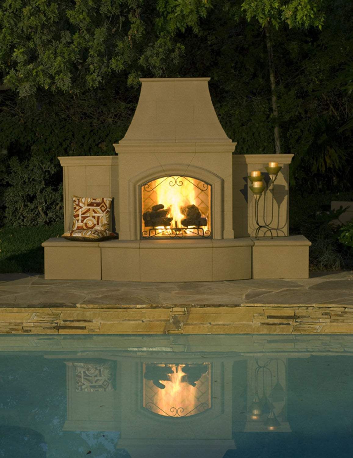Outdoor gas fireplace with cream mantel and arched glass front, burning flames