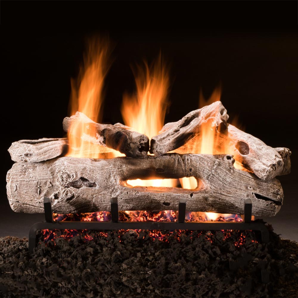 See-through vented gas log set with burning driftwood logs and metal grate