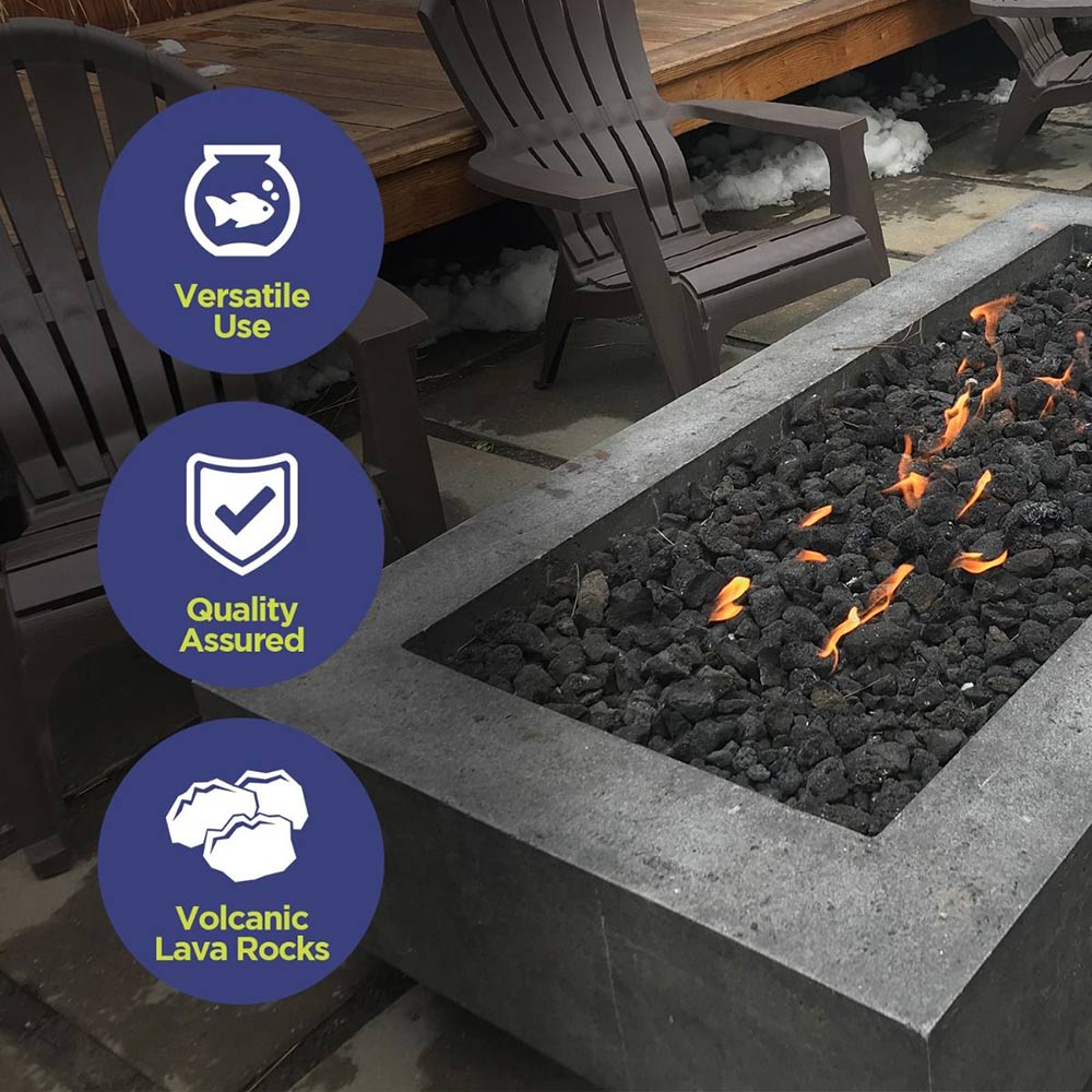 Black lava rock-filled fire pit bed with small flames and ember glow