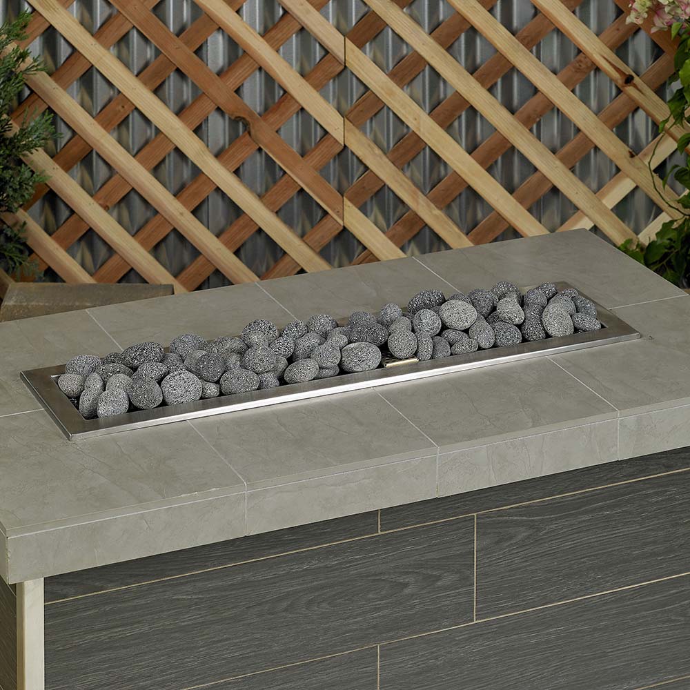 Gray lava fire glass stones on rectangular tray in outdoor fire pit