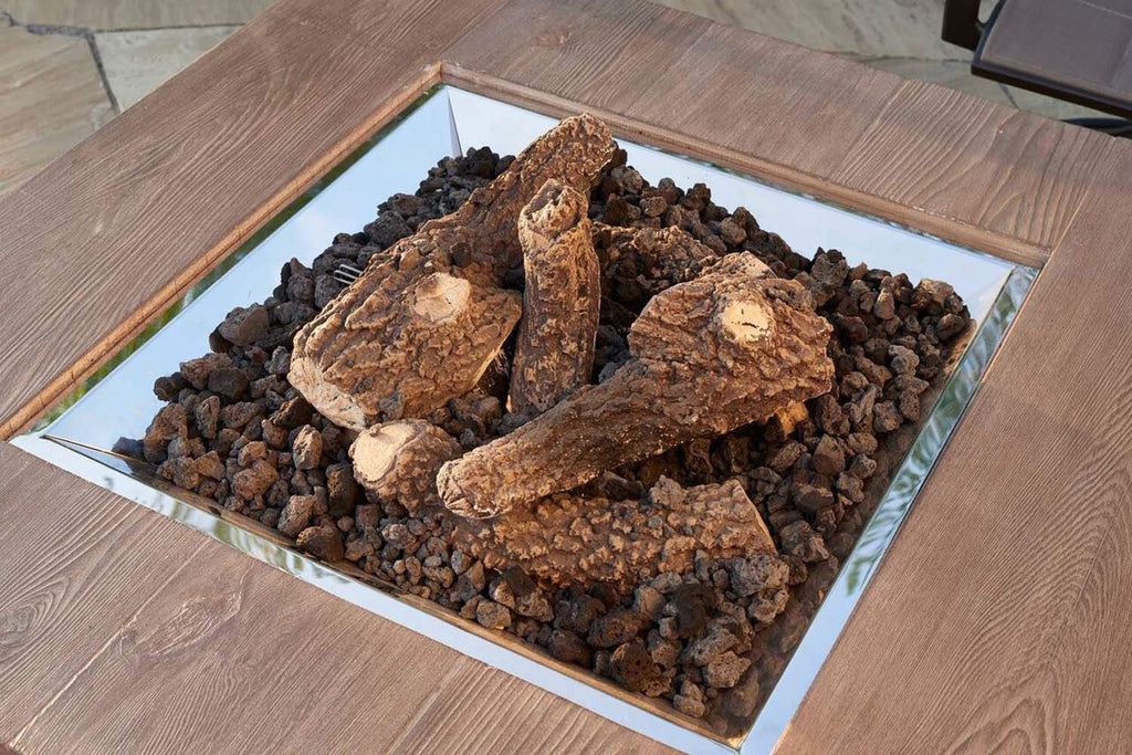 Outdoor gas fireplace log set with brown logs and black decorative fire stones