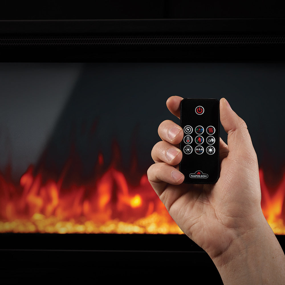 Hand holding black remote control for electric fireplace flame settings