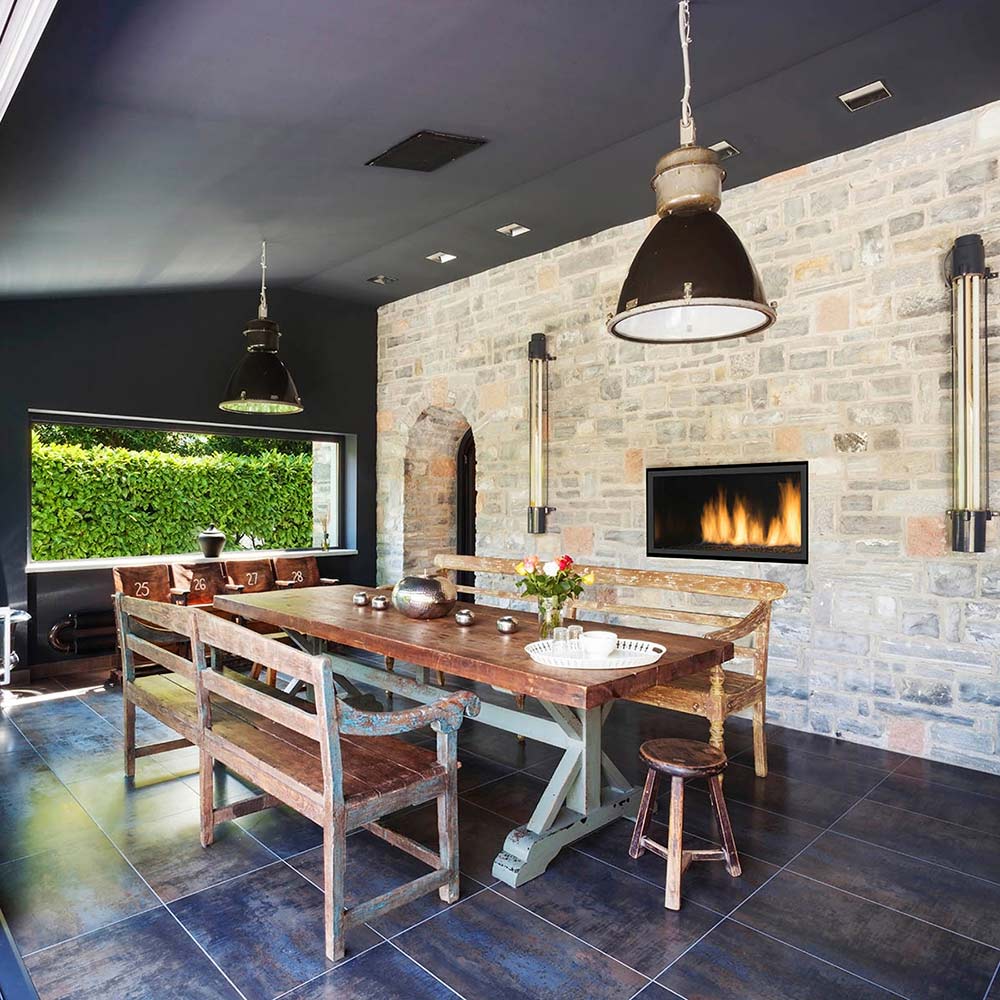 Built-in gas fireplace with flames in stone wall surround, black trim