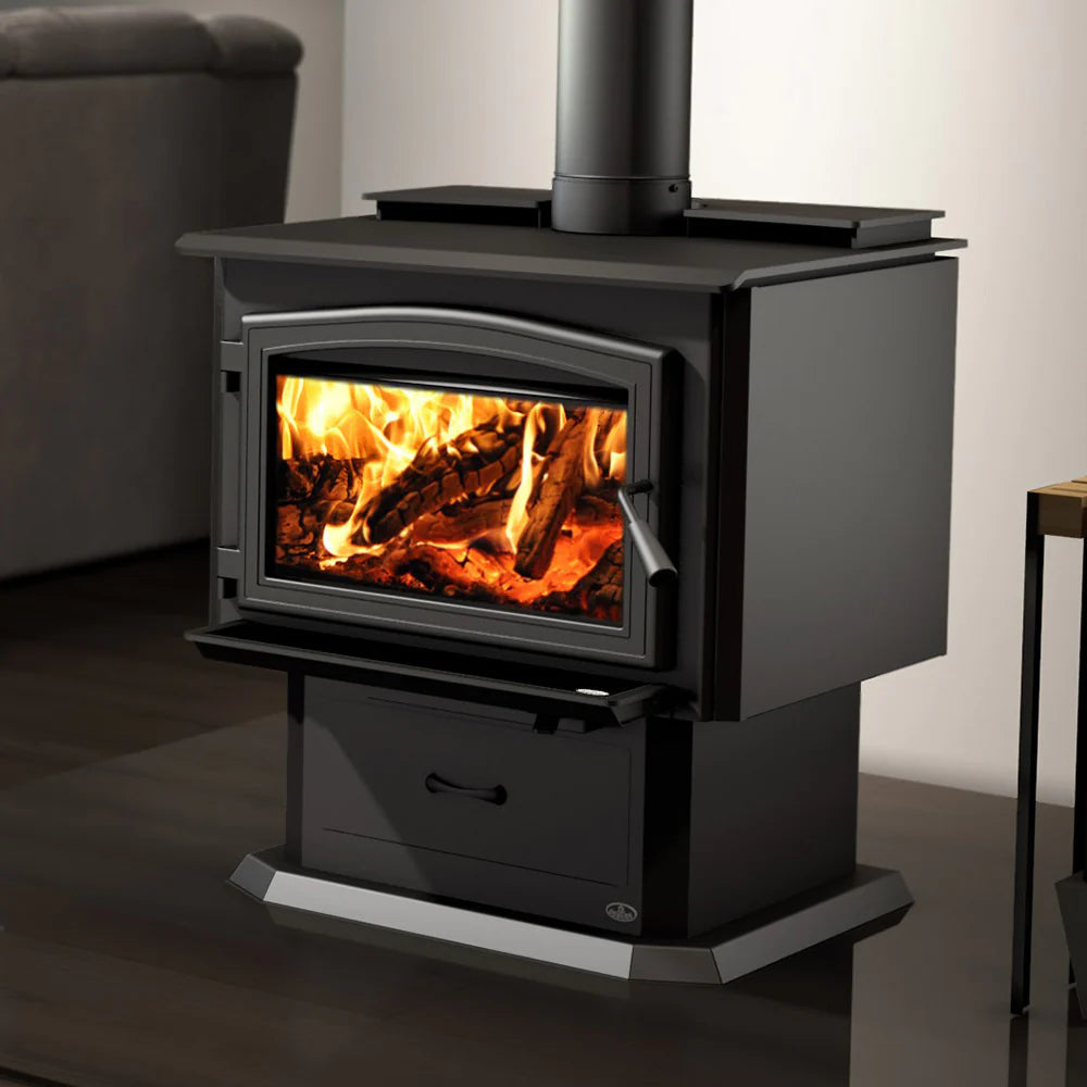 Black door overlay wood stove with blower, glass door and burning firebox visible