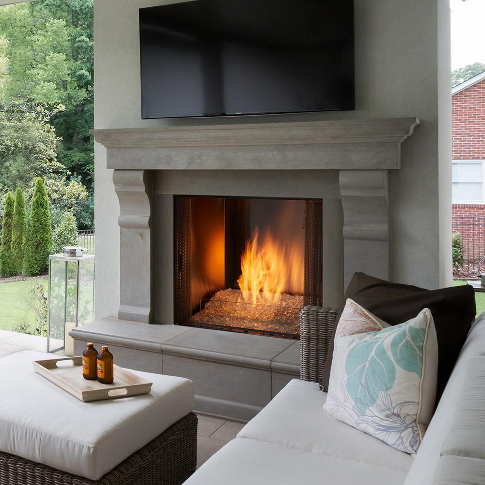 Outdoor natural gas fireplace with grey stone surround and open flame firebox