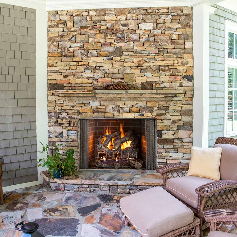 Outdoor gas fireplace firebox with vented log set and stone surround, door open