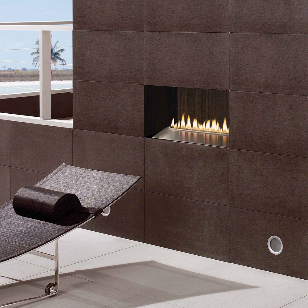 Wall-mounted outdoor gas burner in dark stone surround with active flames