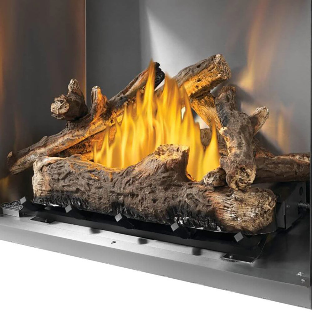 Outdoor gas fireplace log set in firebox with rustic logs and tall orange flames