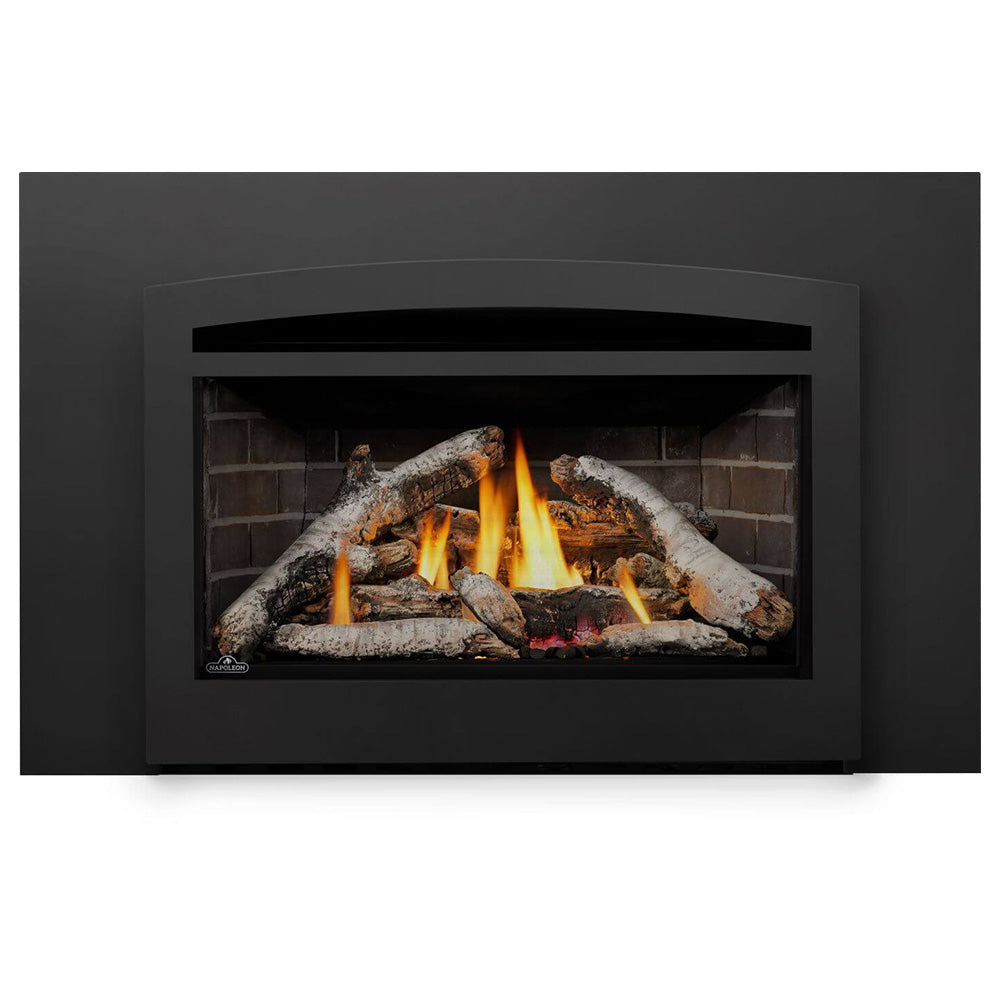 Direct vent gas insert fireplace with burning logs and soot-textured burner area behind glass