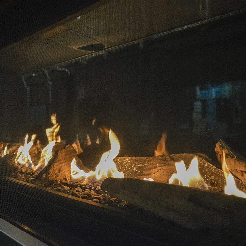 Close-up of glowing flames over clear fireglass media in a linear gas fireplace