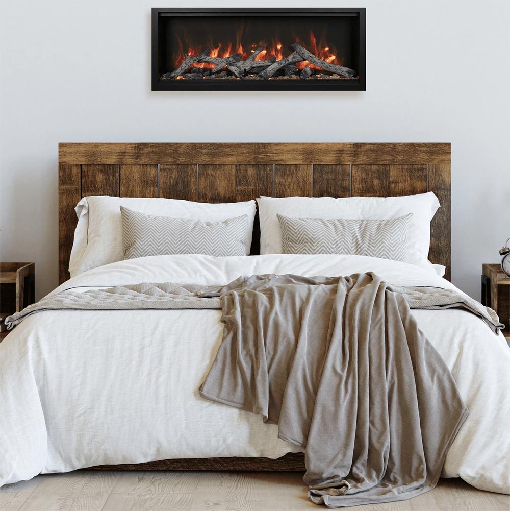 Built-in electric fireplace with black frame and burning logs above a bed