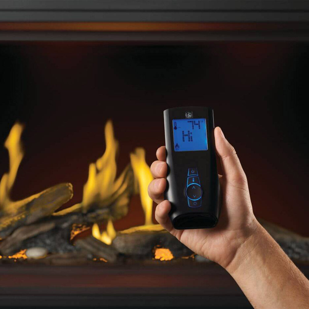 Hand holding remote control for linear gas fireplace with glowing flames