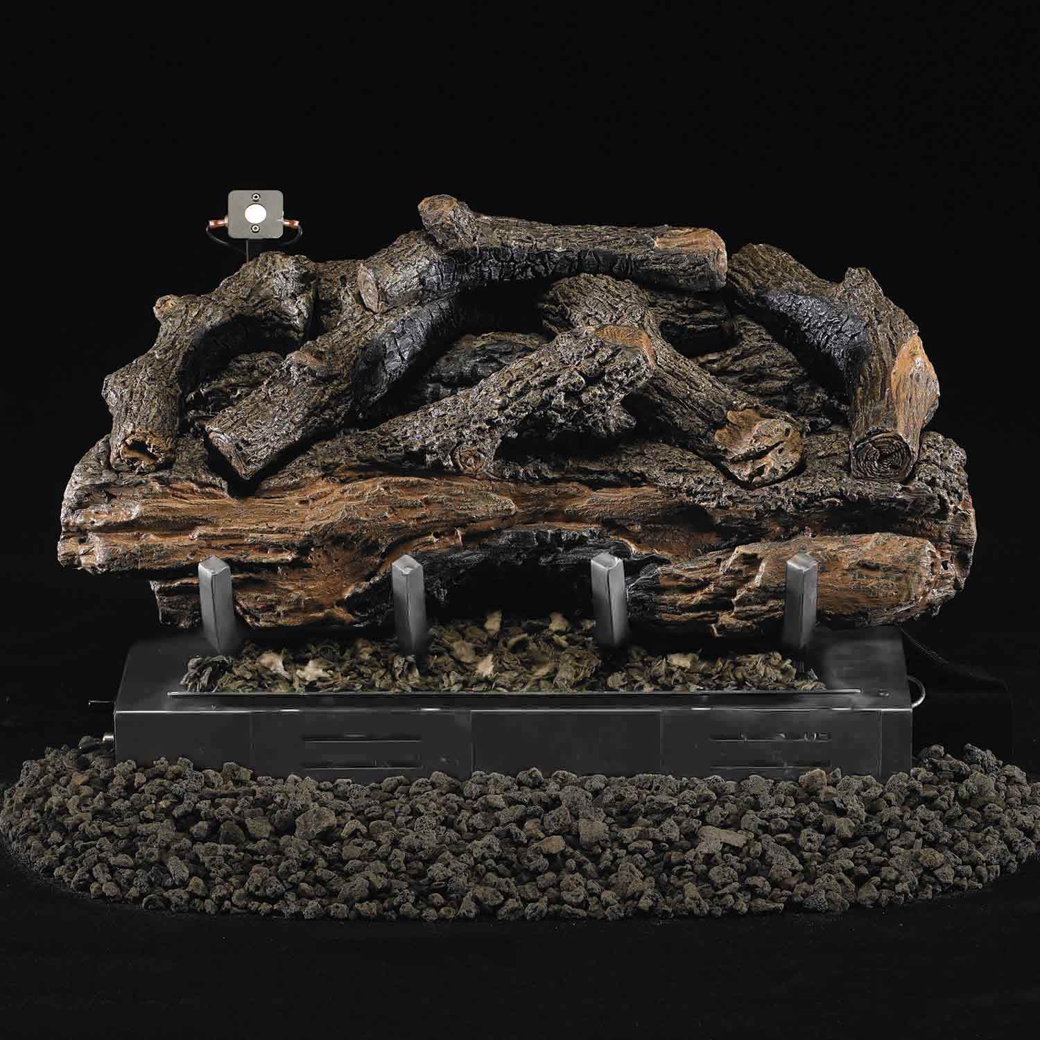 Charred aged ventless gas log set with lit flames over burner pan and black rocks