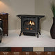 Matte black ventless cast iron gas stove with open glass front and burning burner