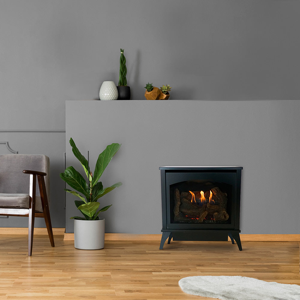 Dark ventless gas stove on legs with glass front showing burning logs
