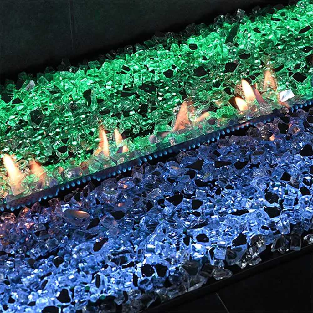 Ventless linear gas burner glowing with green and blue glass media and flames