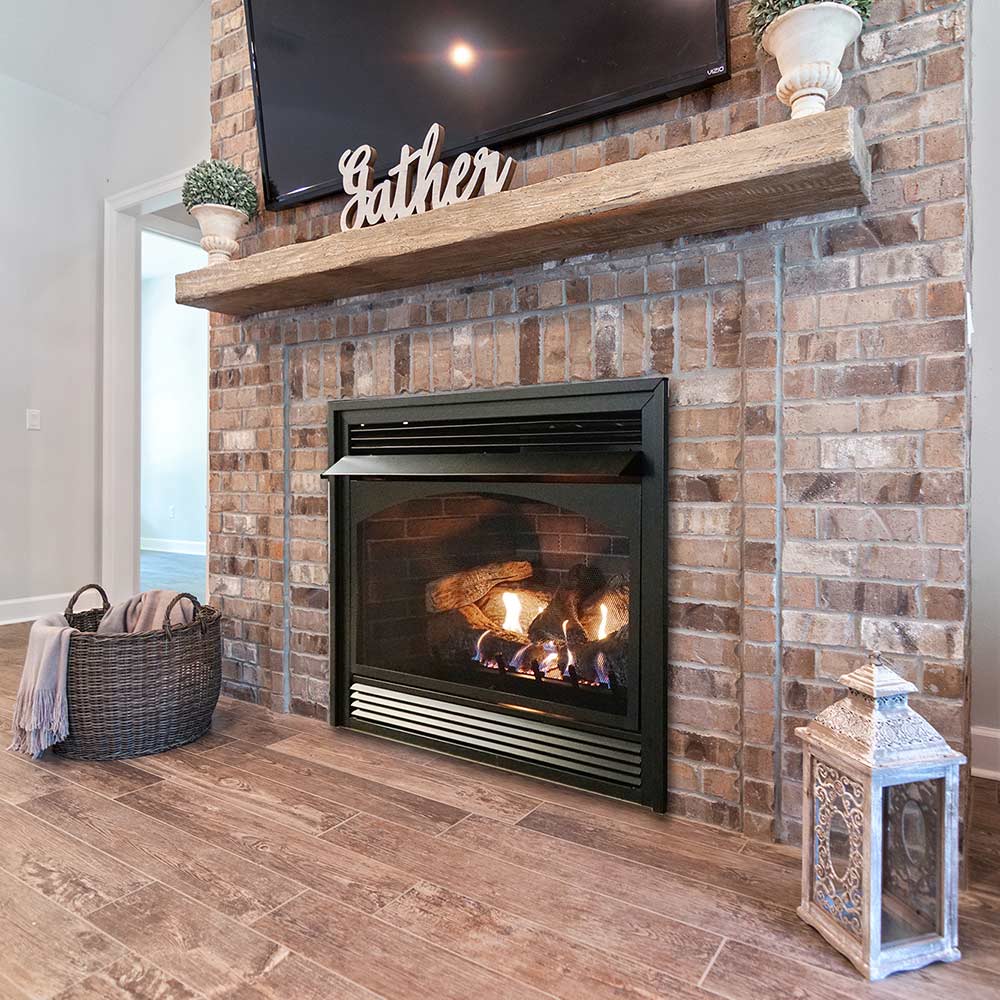 Ventless fireplace with black firebox and glowing log set, in-wall installation