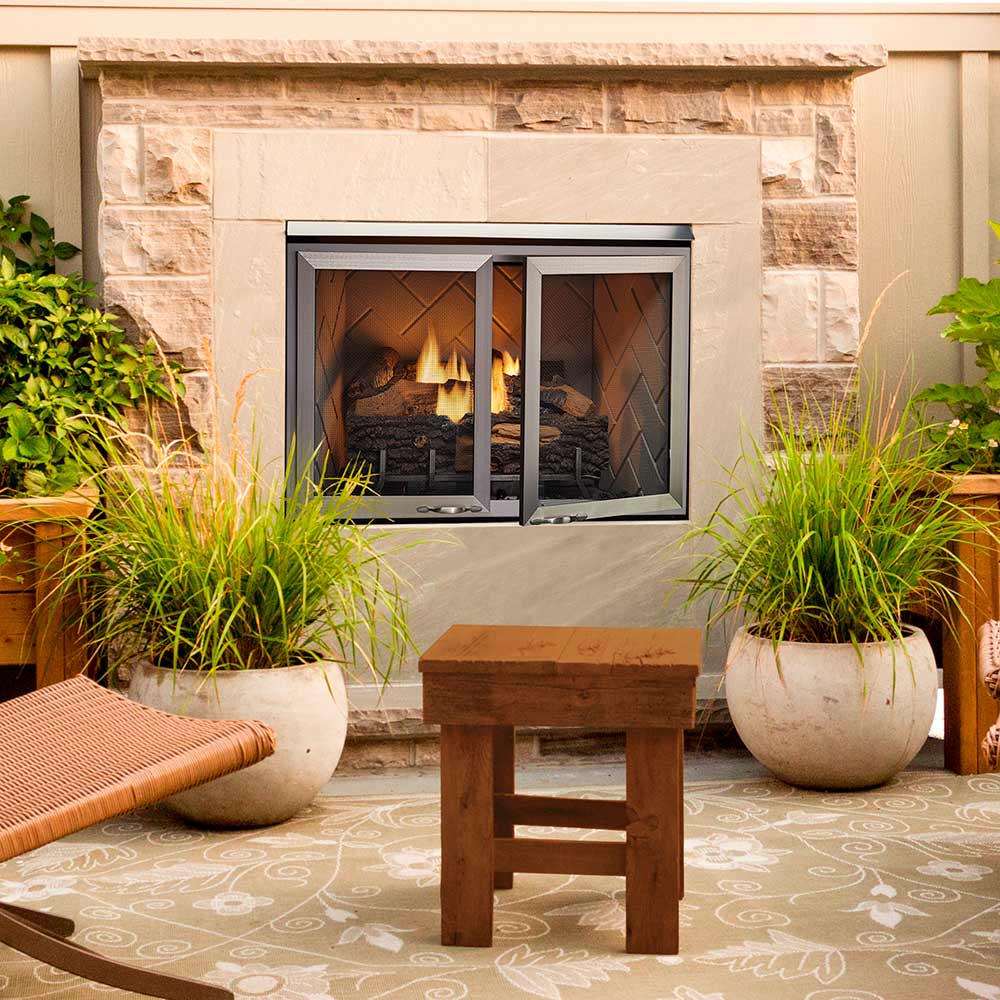Outdoor gas fireplace with stone facade, burning logs, and open mesh doors