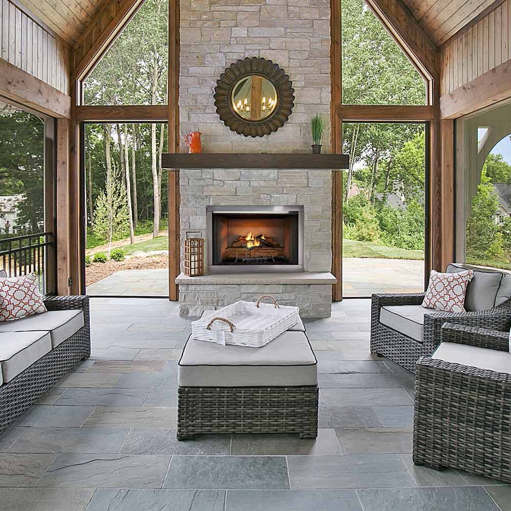 Outdoor gas fireplace with stone surround and burning log set in a rectangular firebox
