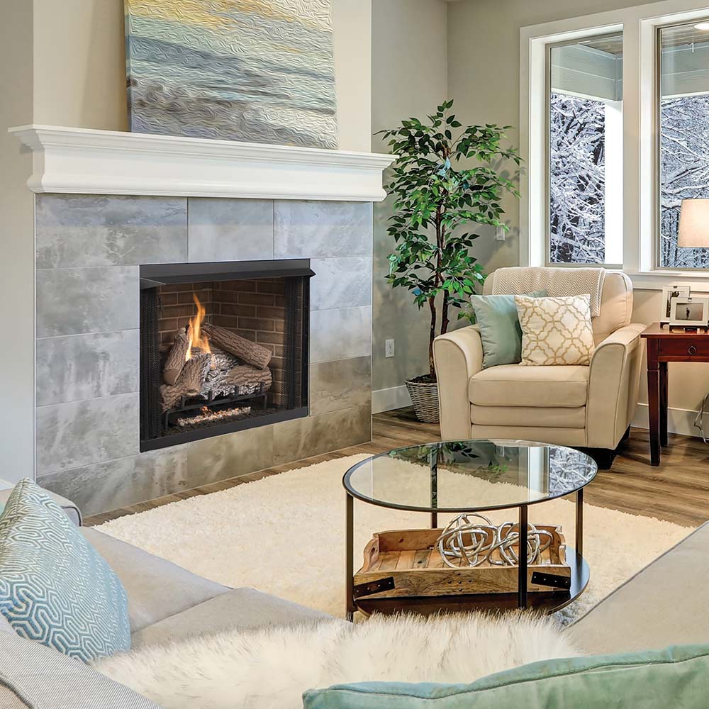 Fireplace insert with burning logs in a dark firebox opening set in light stone