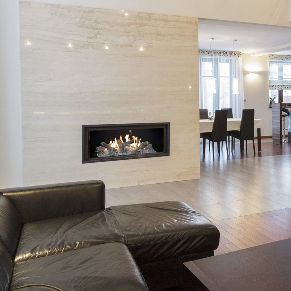Linear gas log set installed in a black fireplace frame with burning logs and embers