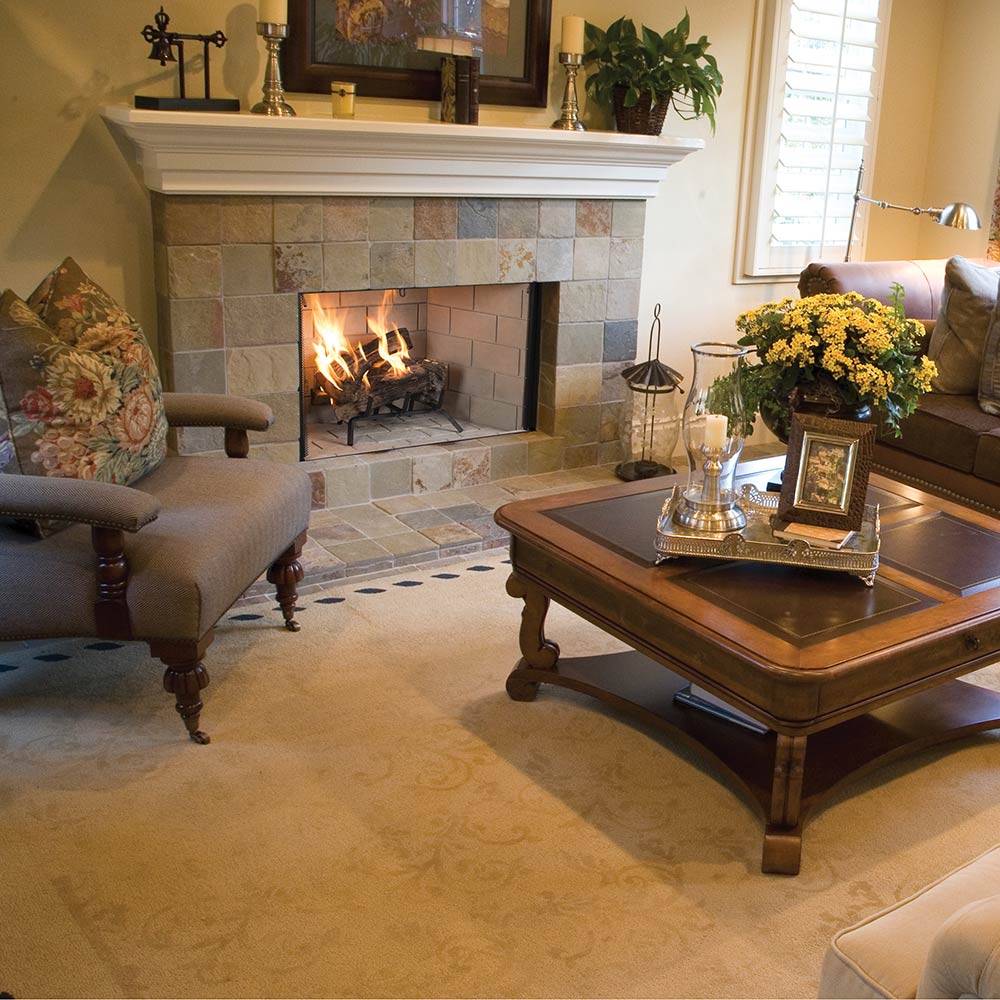Wood burning fireplace with grey stone surround, lit logs, and black fire grate