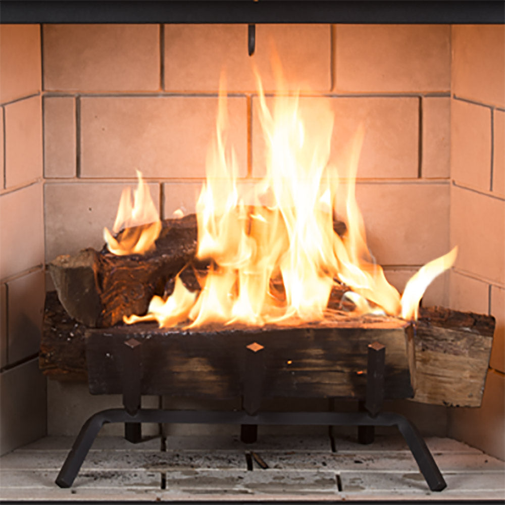 Wood burning fireplace with tall flames, black grate, and grey stacked brick surround