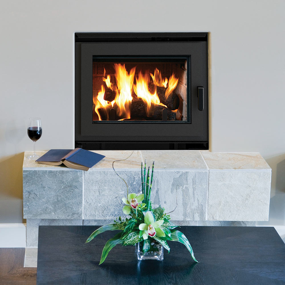 Black wood-burning fireplace on stone surround with flames behind glass door