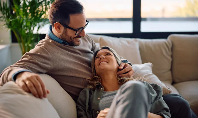 Couple relaxing together on a couch in a cozy living room — finance a new fireplace and enjoy your home more