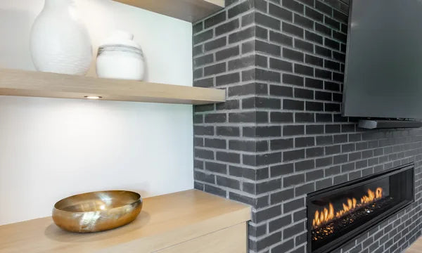 Corner fireplace detail with dark brick surround, built-in shelves, decorative ceramics, and glowing linear flames