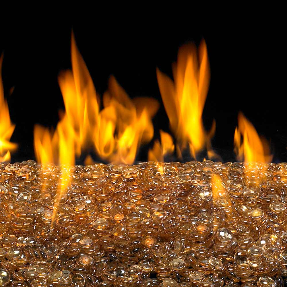 Fire pit glass gems with golden amber glow in a bed of sparkling pieces