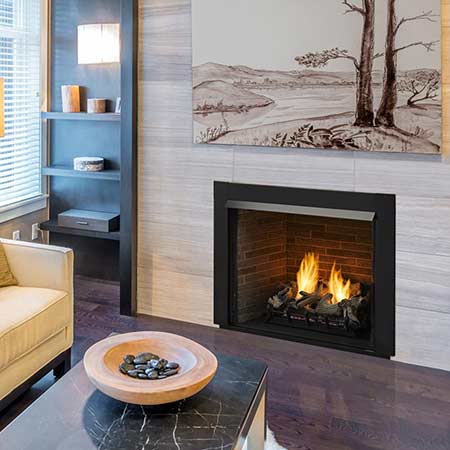 Vent-free gas firebox with black frame and burning log set inside a brick surround