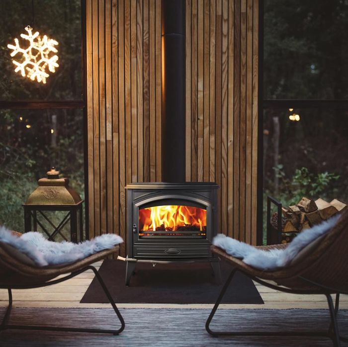 Freestanding wood stove with glass door and visible flames, outdoors
